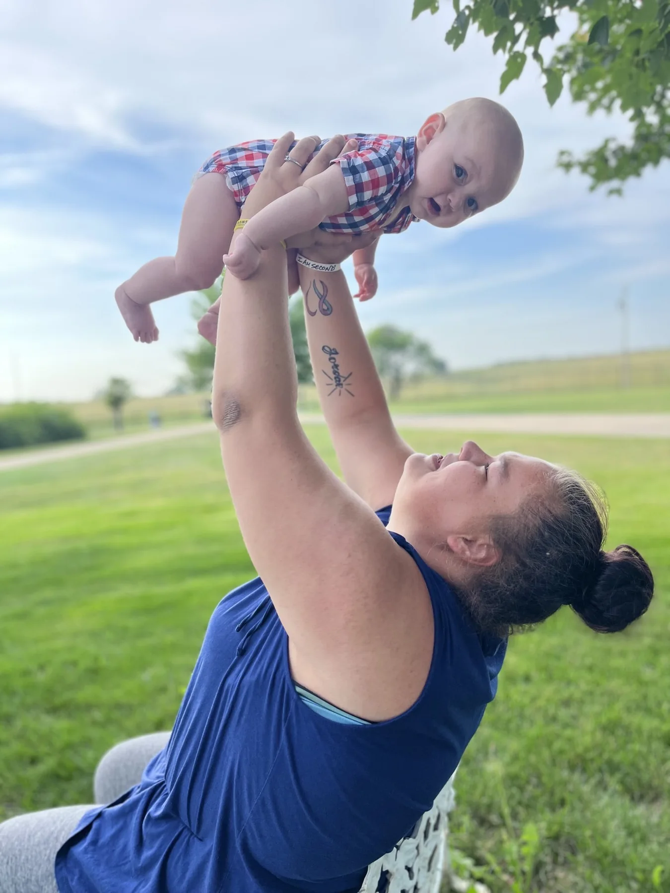 A mother lifting her baby into the air on the lawn outside St. Mary’s Home for Mothers