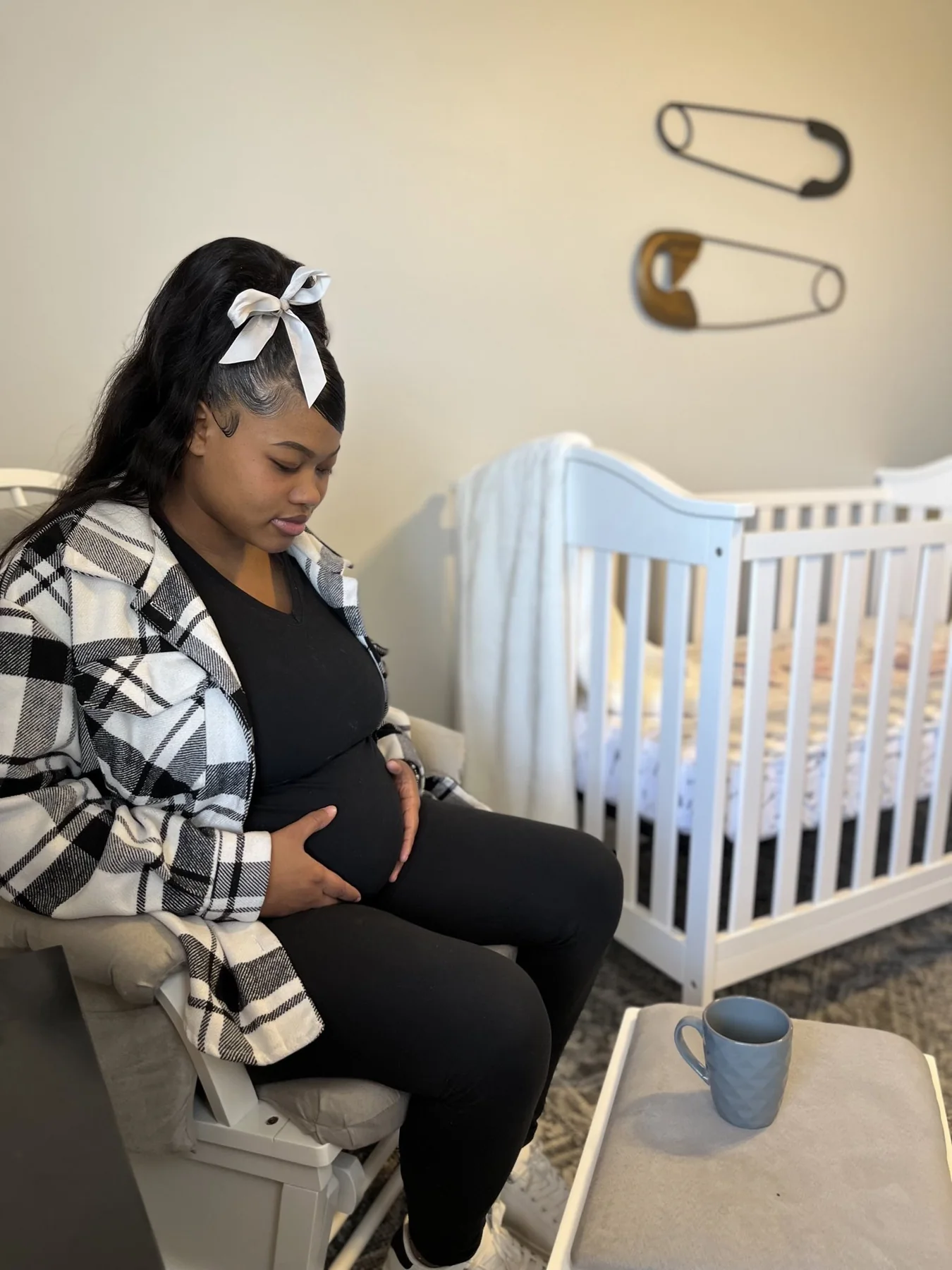 A mother sitting beside a crib in a nursery at the home